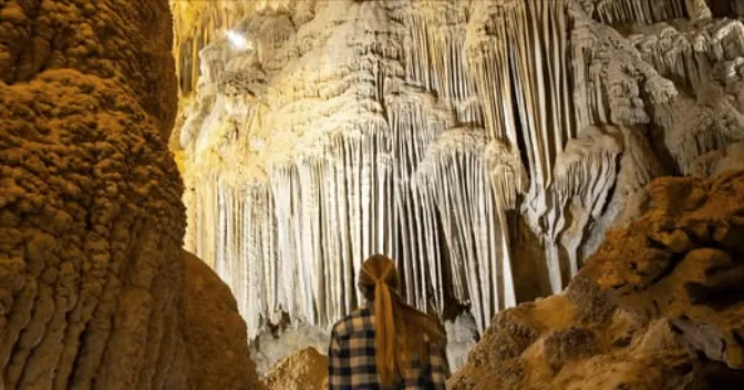 Visitor admiring towering stalactite formations inside Lake Shasta Caverns